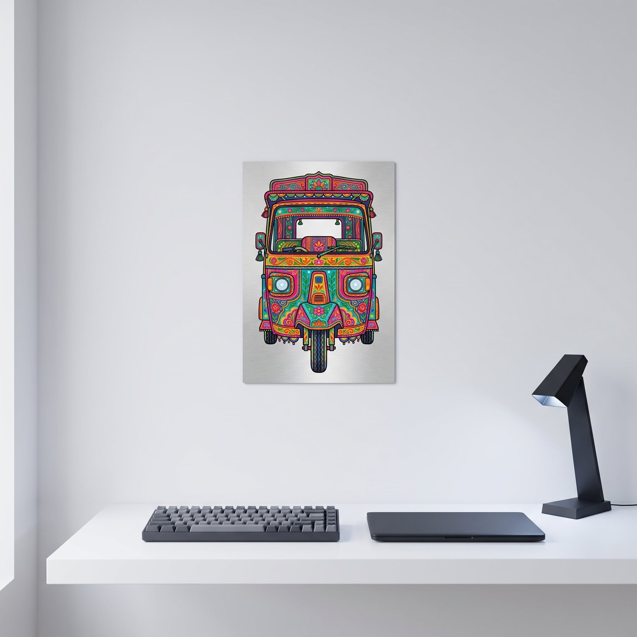 Bright Pakistani Truck Art metal print styled on a clean white wall above a minimalist home office desk with a mechanical keyboard and laptop.