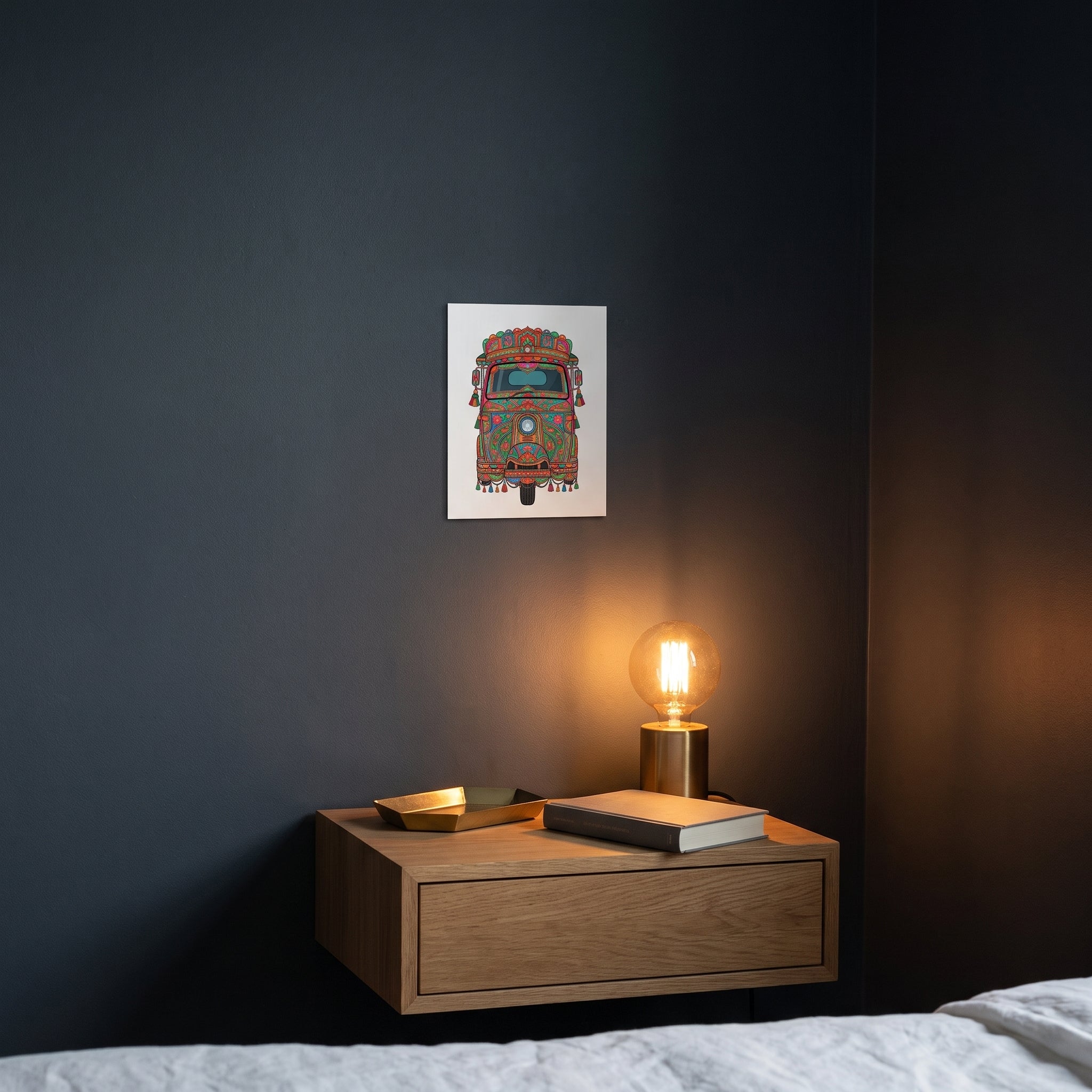 Pakistani auto-rickshaw art metal poster styled on a contemporary bedroom nightstand catching warm ambient light from a lamp.