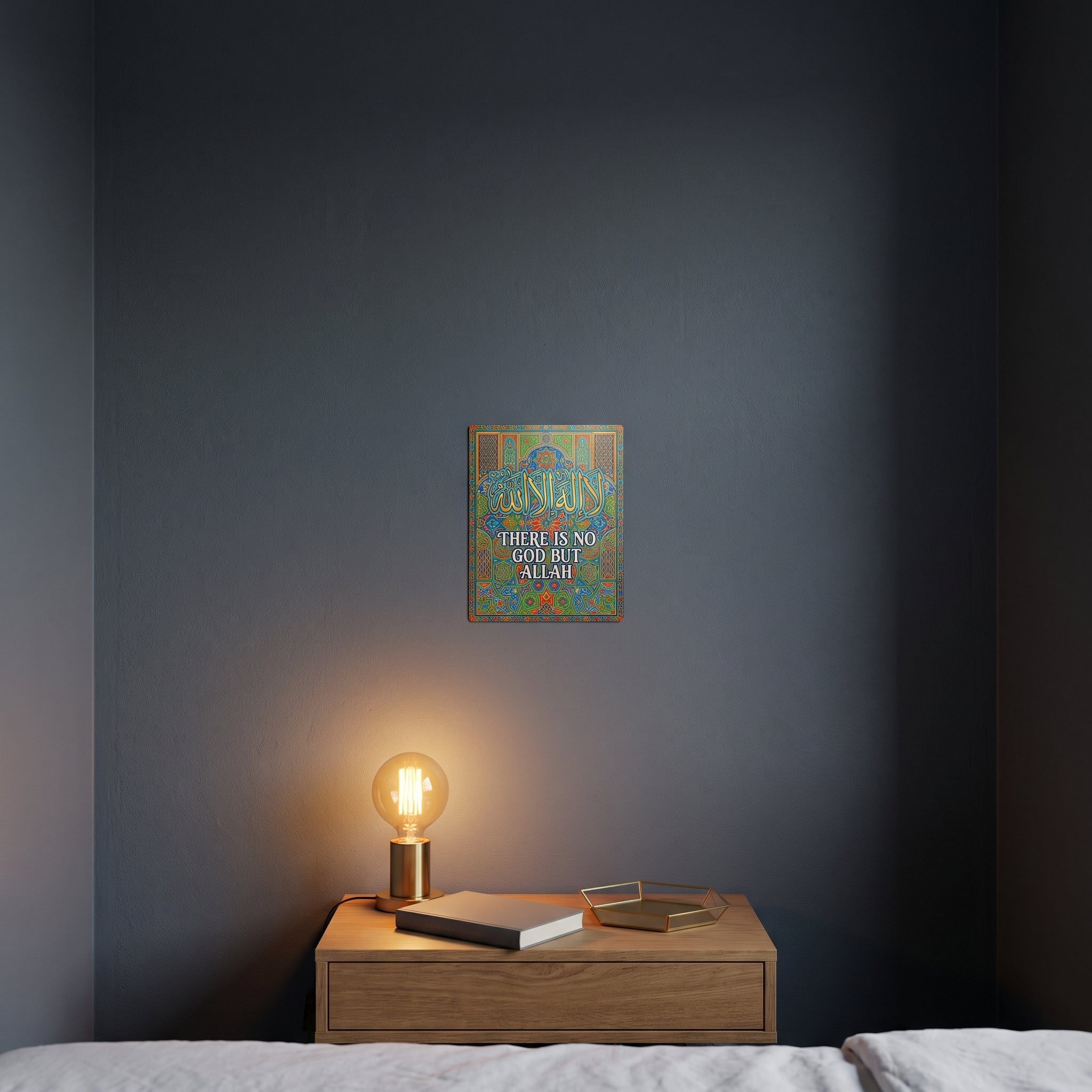 
Pop-art style Shahada phrase metal print catching warm ambient light from a lamp on a contemporary dark bedroom nightstand.
