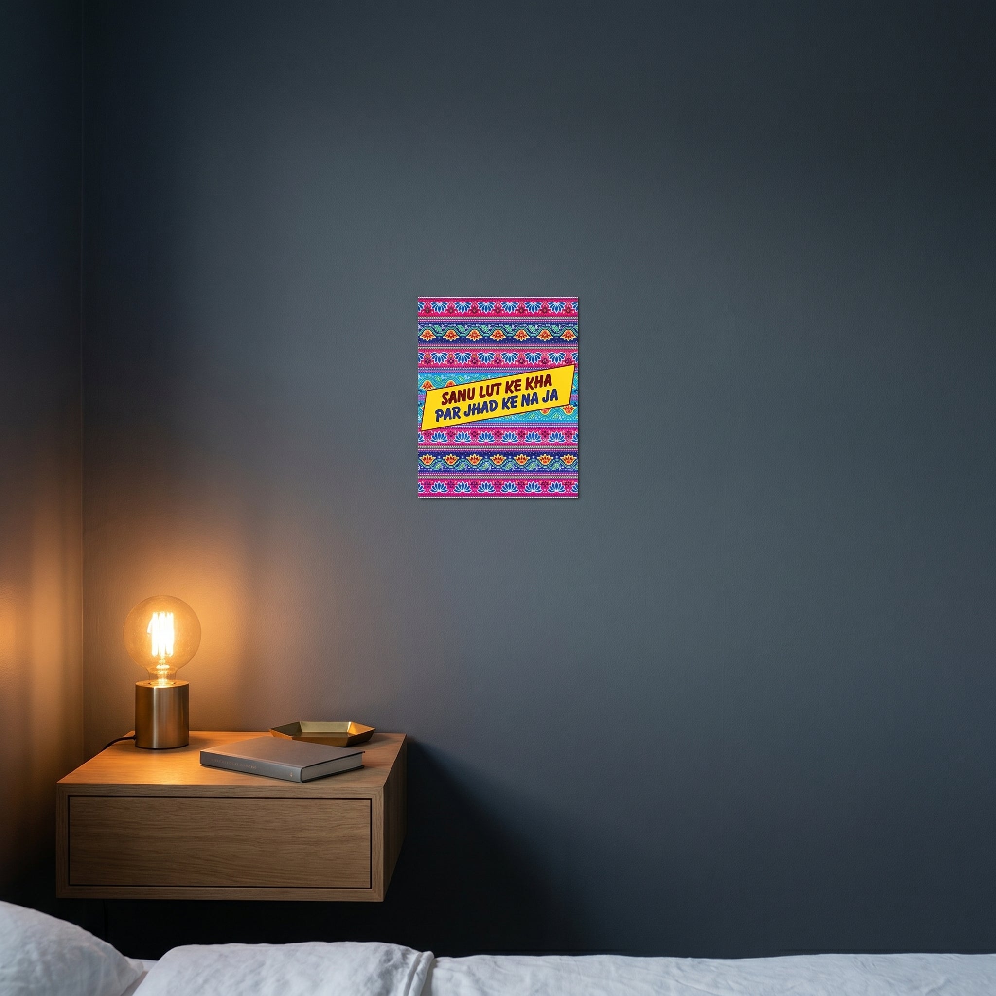 Pop-art style funny Punjabi metal print catching warm ambient light from a lamp on a contemporary dark bedroom nightstand.
