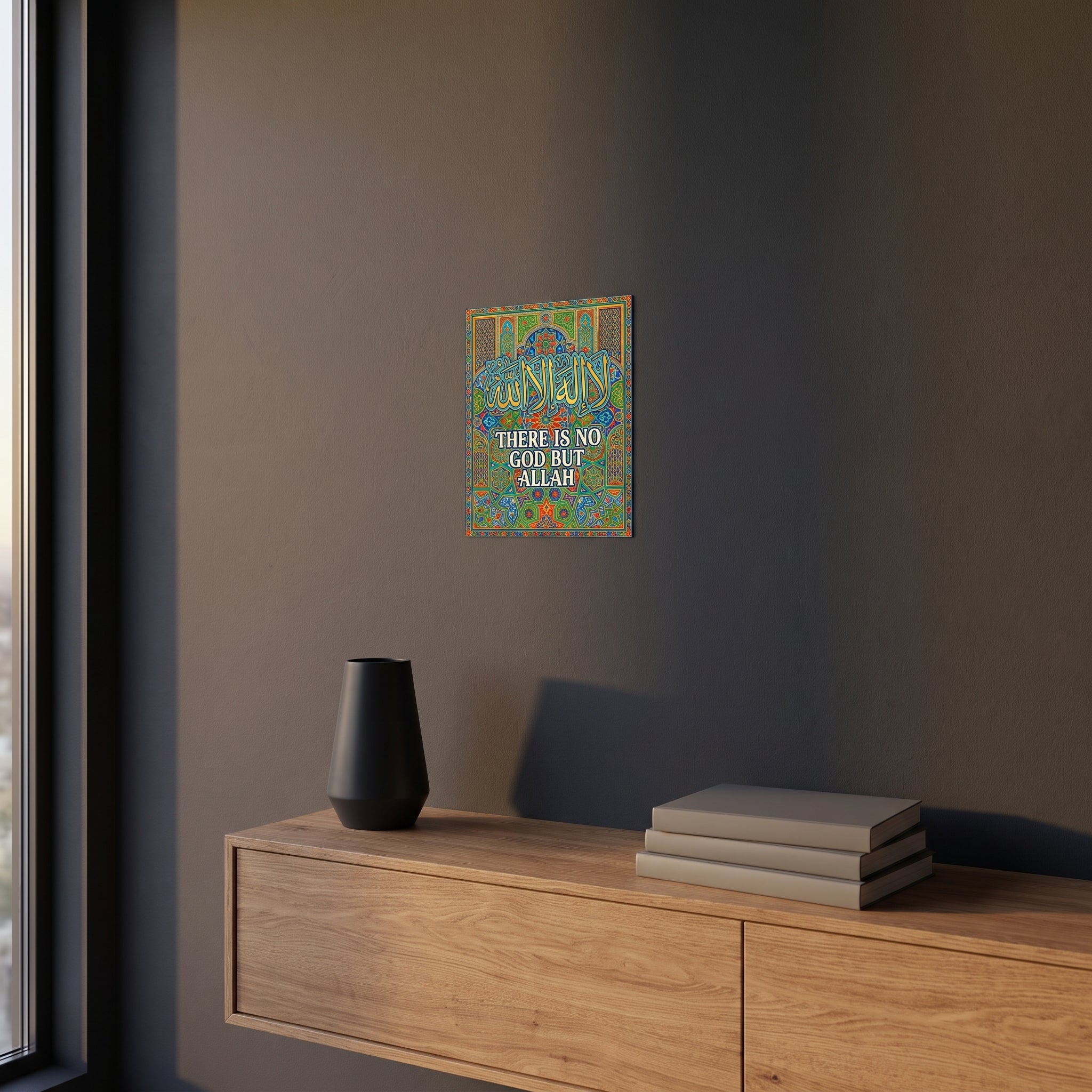 
Pop-art style Shahada phrase metal print catching warm ambient light from a lamp on a contemporary dark bedroom nightstand.
