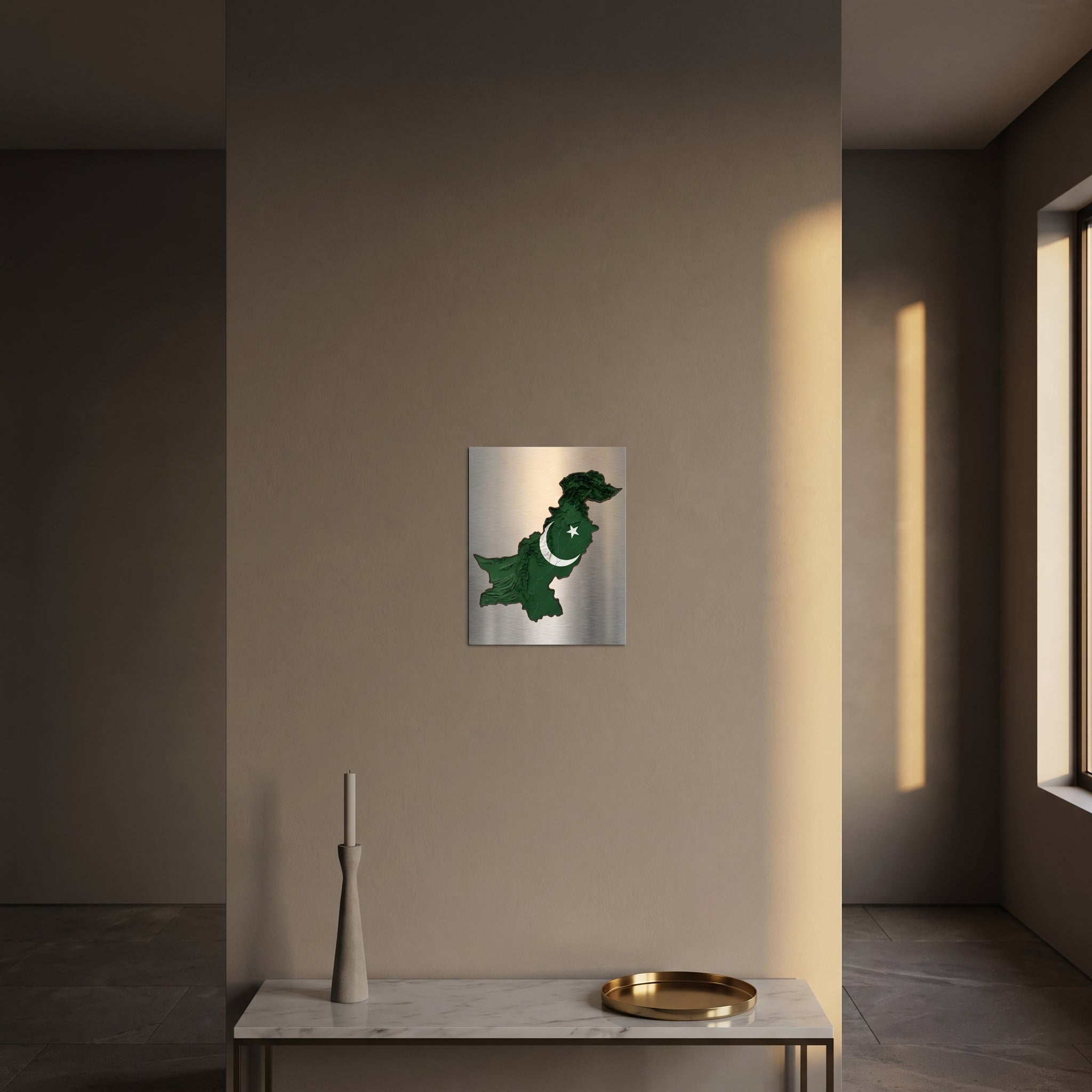 Sleek topographic Pakistan flag heritage metal print catching warm afternoon window sunlight on a textured plaster wall above a table.
