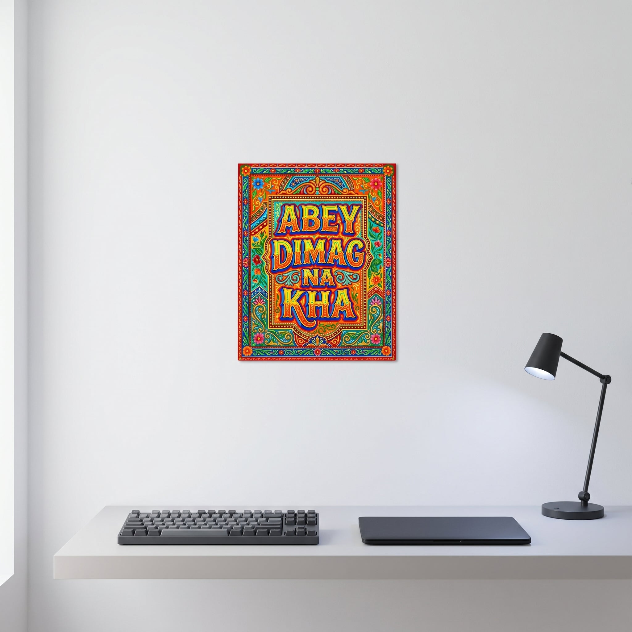 Vibrant South Asian humorous statement aluminum sign styled on a crisp white wall behind a minimalist home office desk setup with a keyboard.