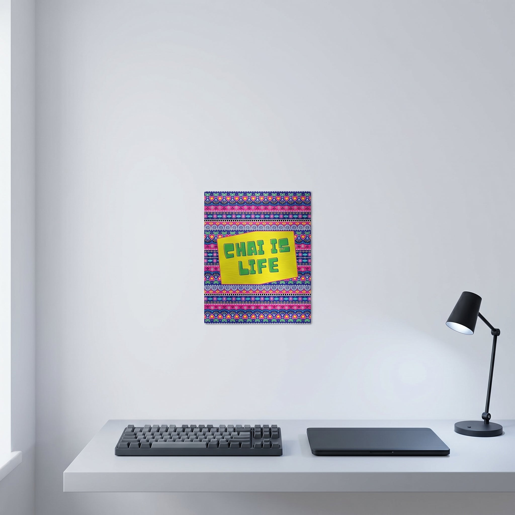  The Chai Is Life artwork displayed on a crisp white wall behind a modern minimalist home office workspace with a keyboard and desk lamp.
