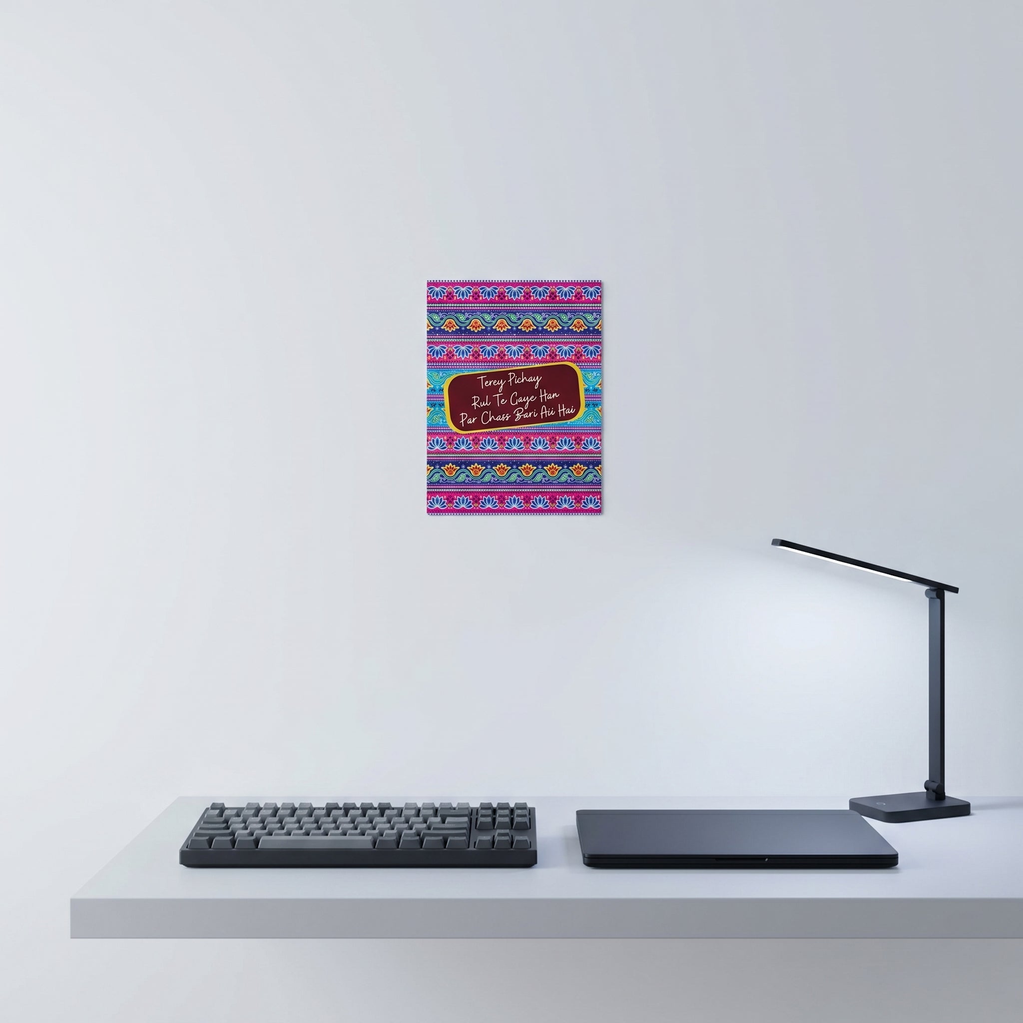 Vibrant Desi culture poster hanging elegantly on a white wall behind a minimalist home office desk setup with laptop.
