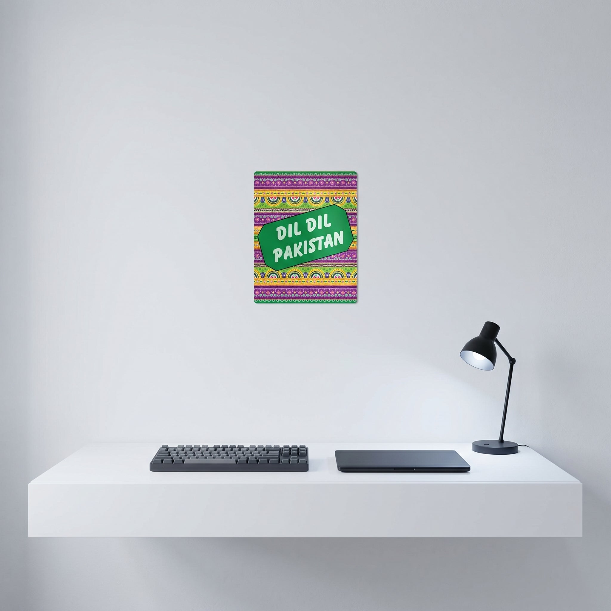 Vibrant Pakistani culture poster hanging elegantly on a crisp white wall behind a modern minimalist home office workspace setup.
