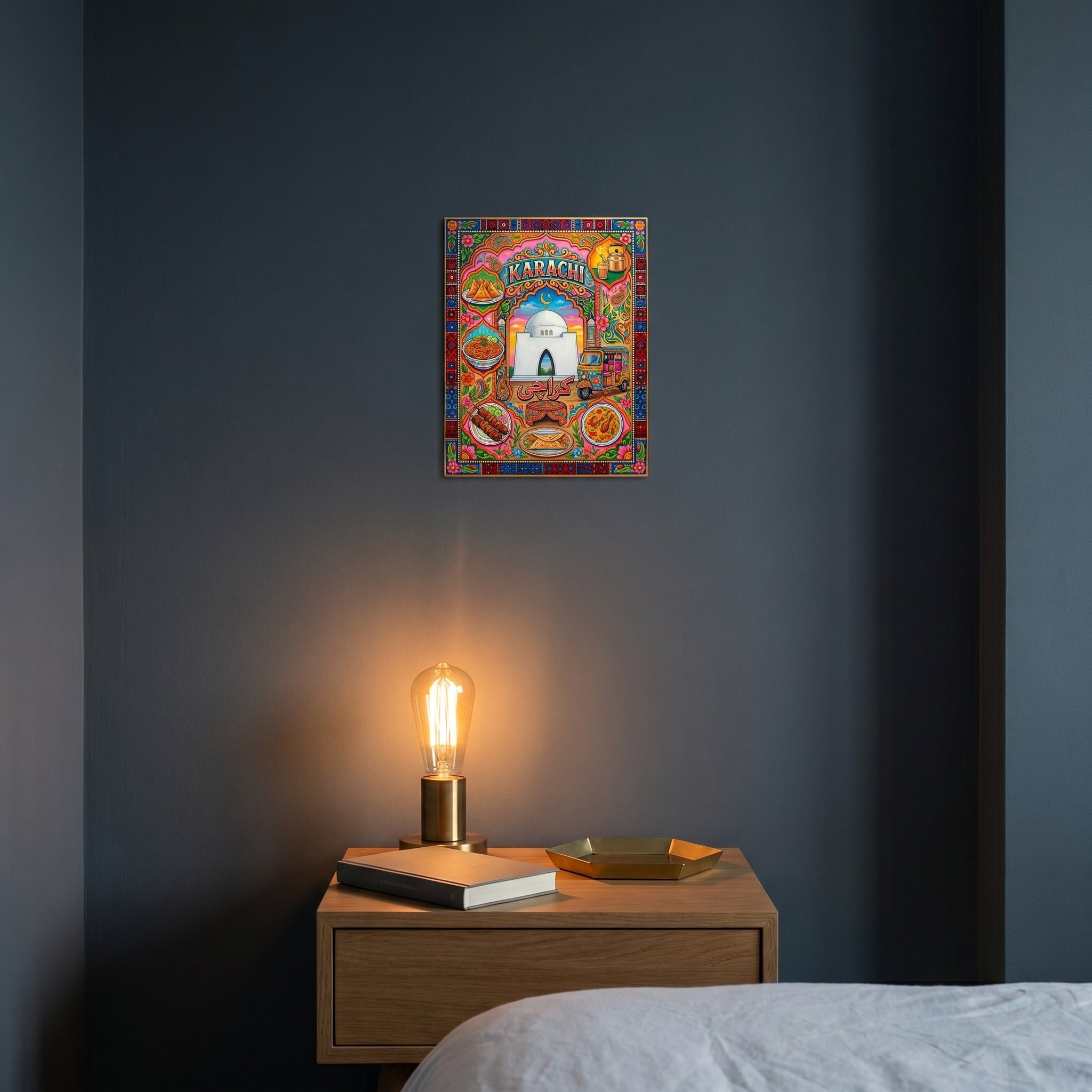 Vibrant South Asian heritage room decor print catching warm light above a wooden nightstand in a moody dark-walled bedroom.