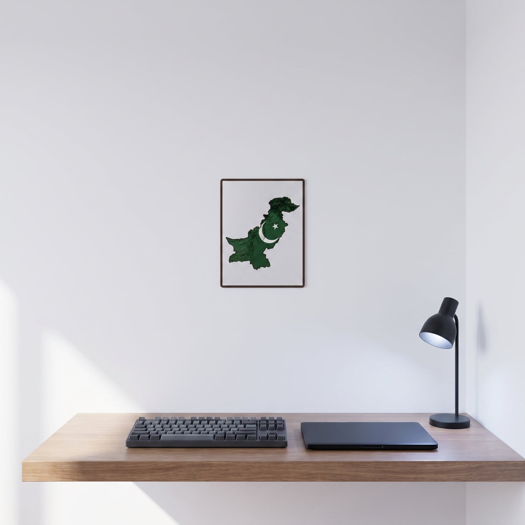 Vibrant Pakistani map statement sign styled on a crisp white wall behind a minimalist home office desk setup with a keyboard.